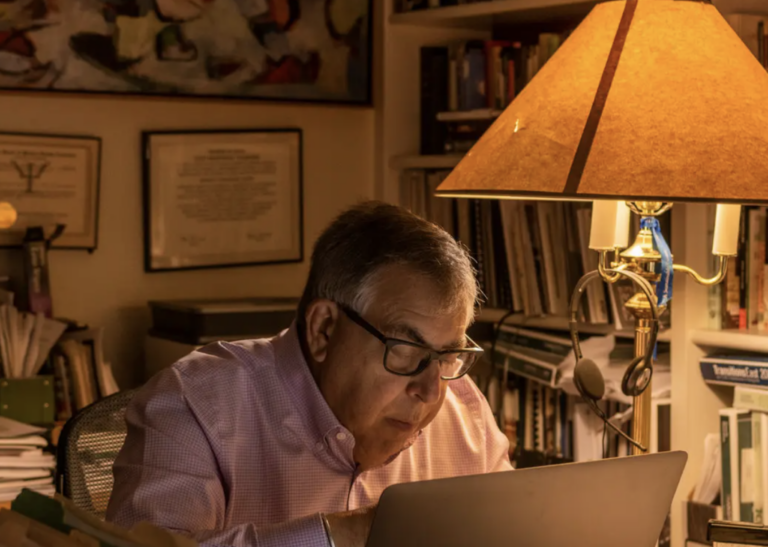 older man at lap top computer next to lamp in office