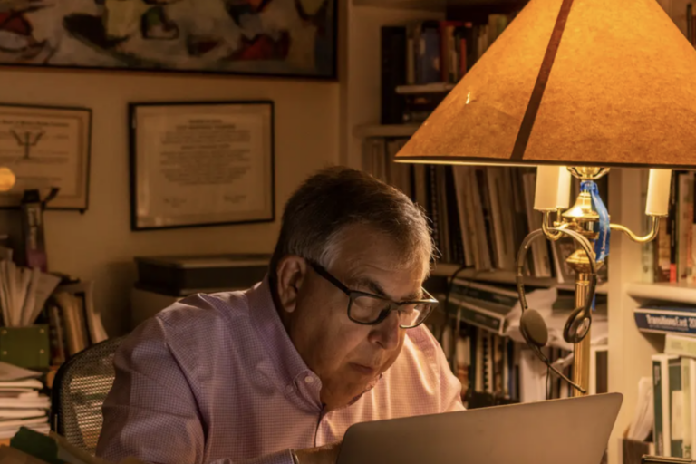 older man at lap top computer next to lamp in office